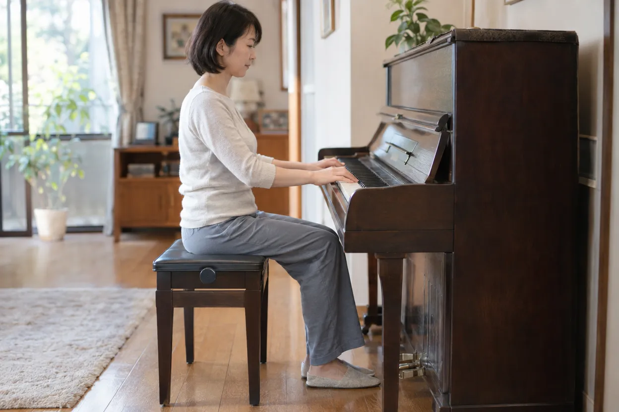 足の裏を床につけ、椅子の高さを合わせてピアノを弾く女性を横から見た様子